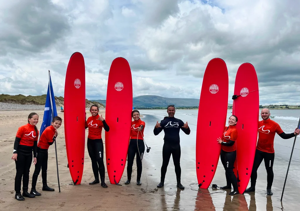 Adults posing with surf board on beach