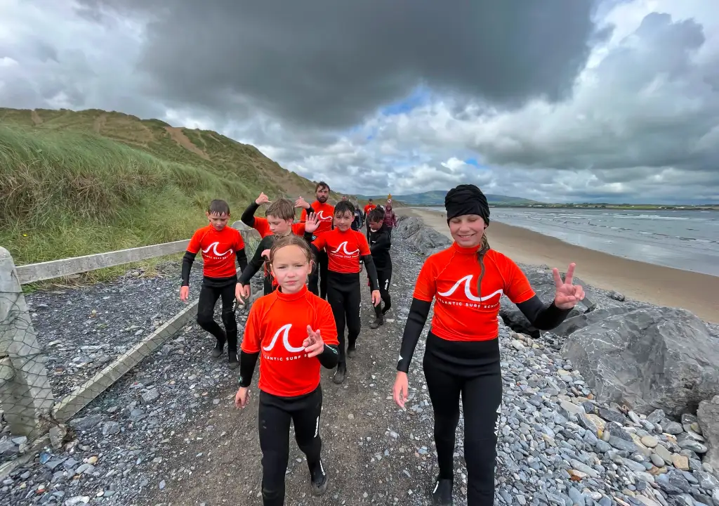 children walking on beach after surfing session