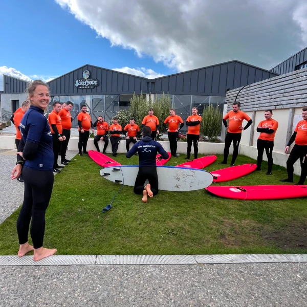 Group of adult standing with their surf board and listening to guides instruction