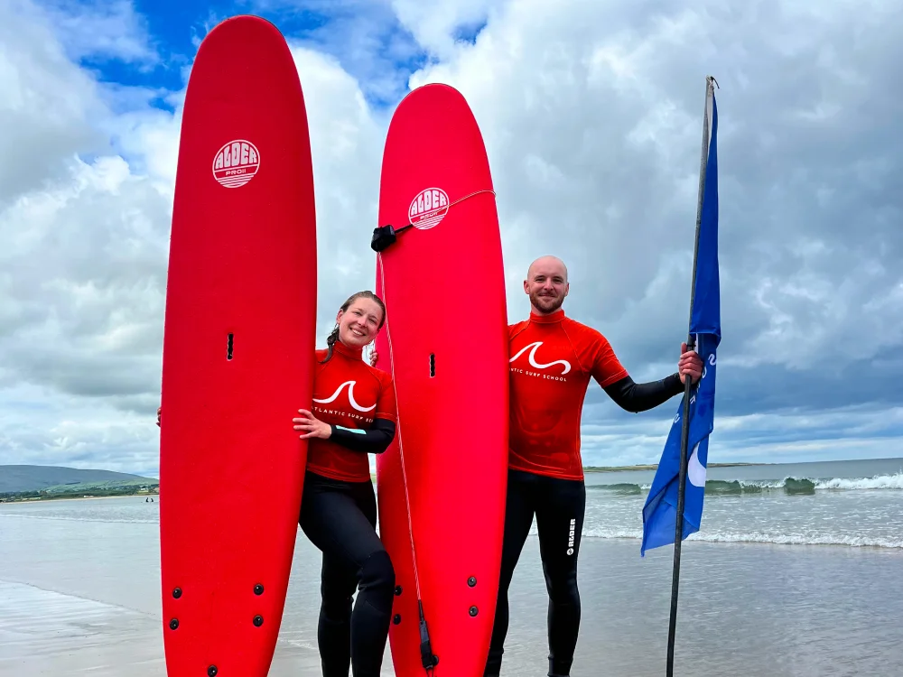 A couple standing on beach holding surfing boards