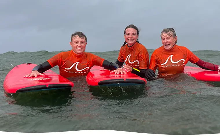 Three members of a family posing with their surf boards in the ocean