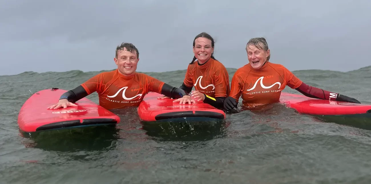 Three members of a family posing with their surf boards in the ocean