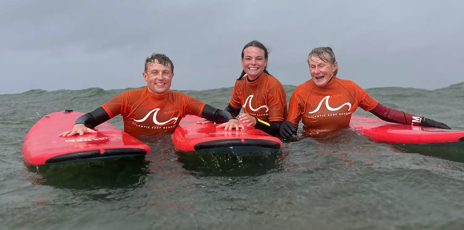 Three members of a family posing with their surf boards in the ocean